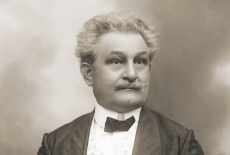 black and white photo of Jean Sibelius, wearing a black coat, white shirt, and black bow tie