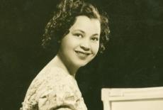 A teenage or 20 something Margeret Bonds posing at the piano in a sepia-toned picture