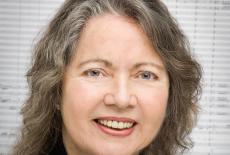 A headshot of the composer Ellen Taafe Zwilich with sheet music as the backdrop