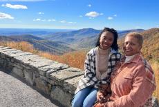 A young woman and her mother sit, smiling, on a stone bench with views of Virginia mountains in the background.