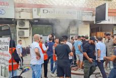 People gather as smoke rises from a mobile shop in Sidon