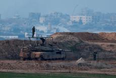 Israeli soldiers stand on a tank, as seen from the Israeli side of the border