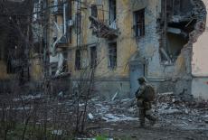 Ukrainian serviceman walks near an apartment building damaged by Russian military strike in the frontline town of Kostiant...