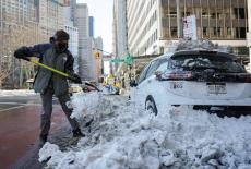A person cleans snow from their vehicle in New York City