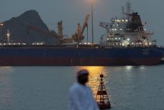 A man sits on the waterfront as vessel sits at anchor inside Sultan Qaboos Port in Muscat