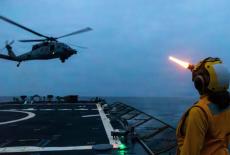 A U.S. sailor signals to an MH-60S Sea Hawk helicopter