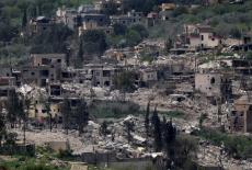 Damaged buildings on the Lebanese side of the Israel-Lebanon border as a armed vehicle stands, after a 10-day ceasefire be...