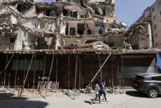 People walk in front of a damaged building in the southern suburbs of Beirut