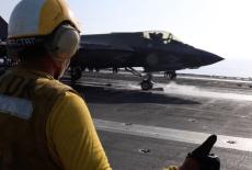 still image released by U.S. Central Command (CENTCOM) shows shows a flight deck crew member signaling an F‑35 jet on an a...