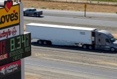 Semi drives past sign showing fuel prices