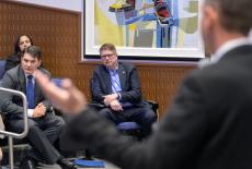 Two men in suits listening to someone speak