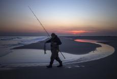 A resident goes to return a striped bass back into the waters off Breezy Point after making the catch along the Queens bea...