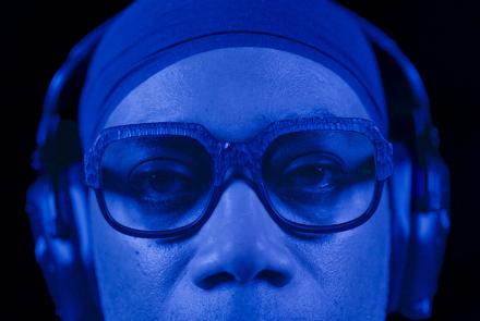 Blue-lit person wearing over-ear headphones against a dark background.