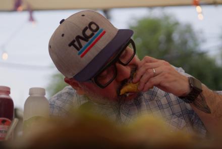 Man in baseball cap eating a taco