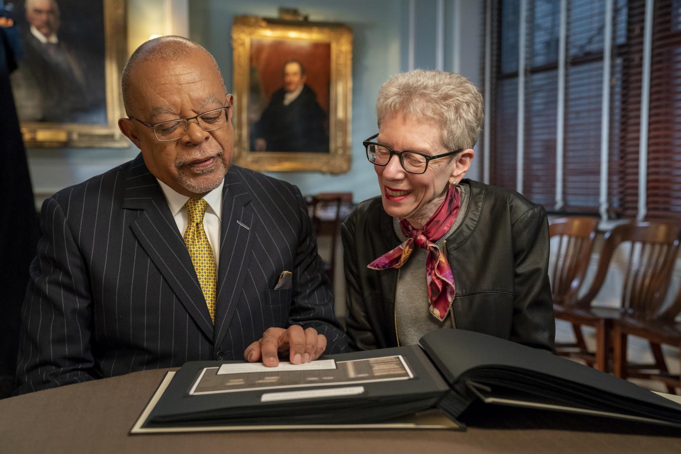 Dr. Gates looks at a book with Terry Gross.