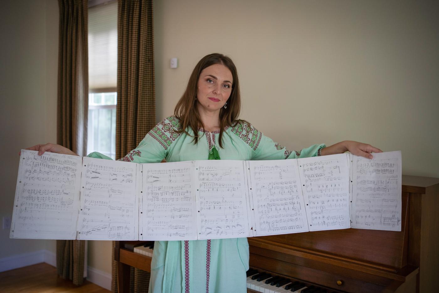 Olha Abakumova unfurls some of her Ukrainian sheet music. She was able to find a piano — free on Facebook — for her new home in a Boston suburb, where she practices her Ukrainian arias.