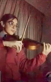 Lubna Alyaan plays hers violin, wearing a red sweater.